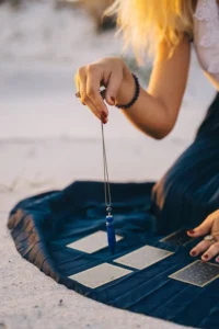 The image shows the use of a pendulum during Tarot card divination.